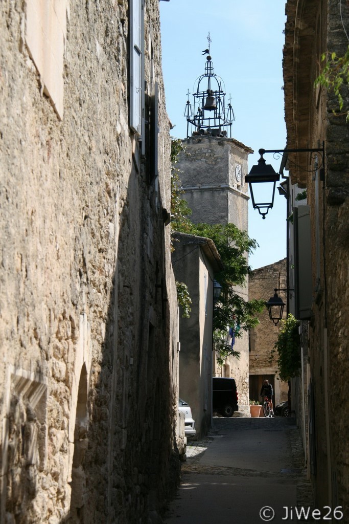 Du fond de la rue de l'église, le campanile en fer forgé surmonté de 5 croix de la Tour de l'Horloge