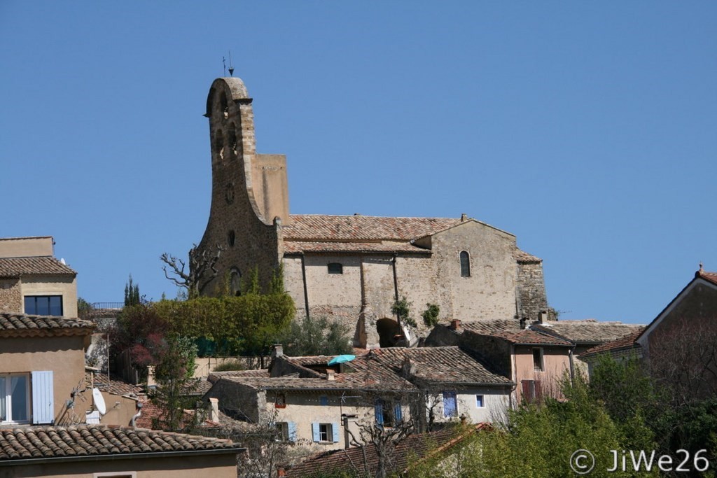 Vue du parking à l'entrée, l'église Saint-Michel et son clocher-peigne.