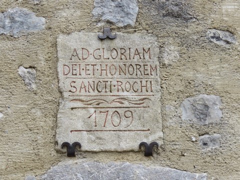 Cette pierre votive intégrée dans la façade nous dit " À la gloire de Dieu et en l'honneur de Saint-Roch. 1709"