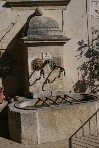 Cette fontaine est adossée à la façade du café-bistrot "la maison d'Eugène"