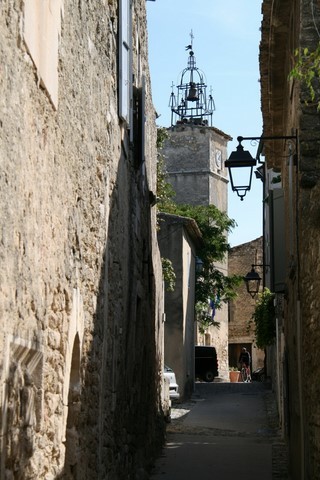 Du fond de la rue de l'église, le campanile en fer forgé surmonté de 5 croix de la Tour de l'Horloge